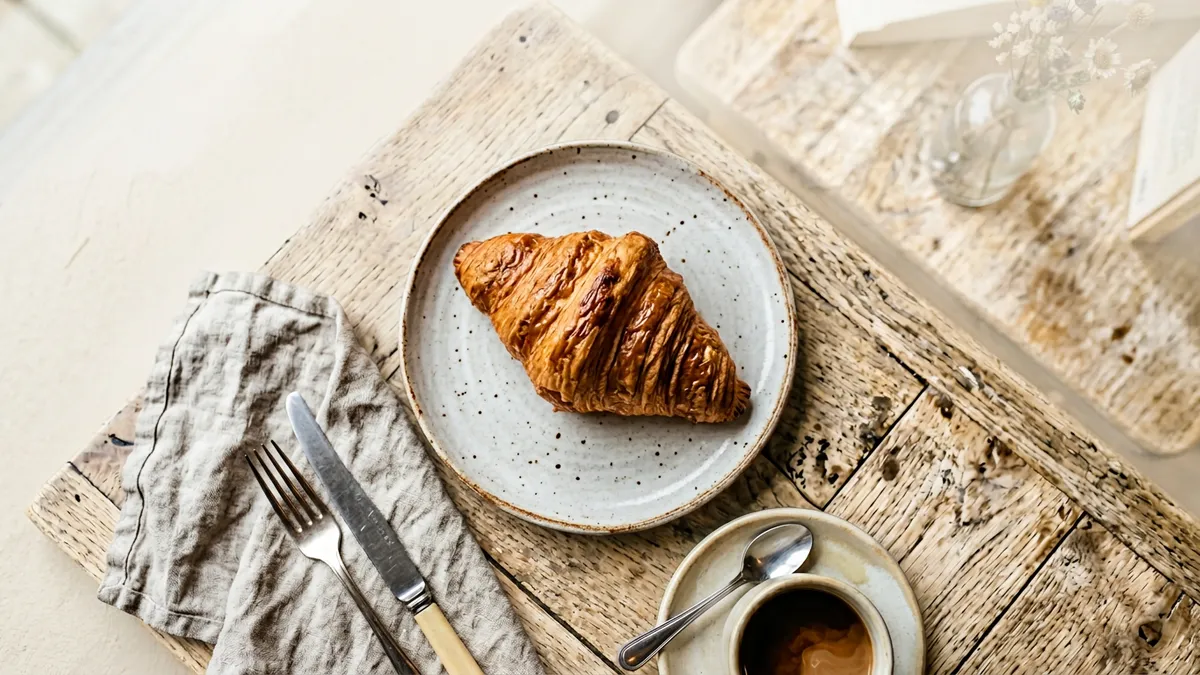 Croissant recién horneado sobre una mesa de madera
